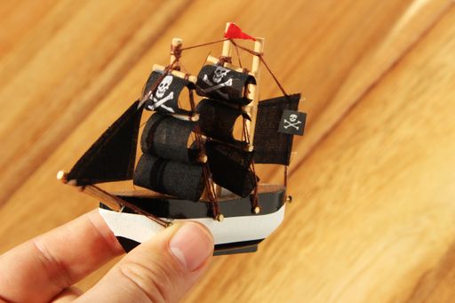 A high angle shot of a person playing with a pirate ship toy over a wooden surface