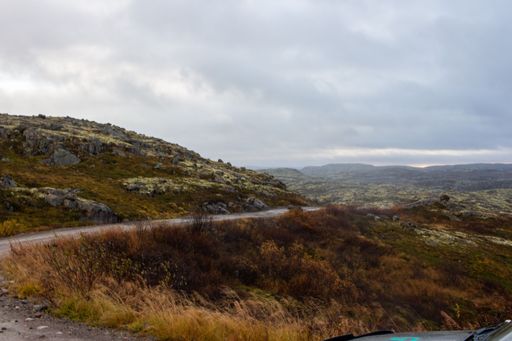 A landscape of a road between canyon hills under gray cloudy sky on the horizon