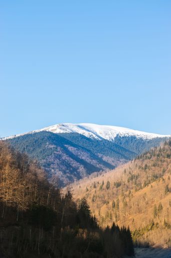 A breathtaking view of a mountain range covered in snow, under the clear blue sky