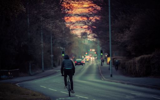 A cyclist riding on an asphalt road in Cambridge at Sunset
