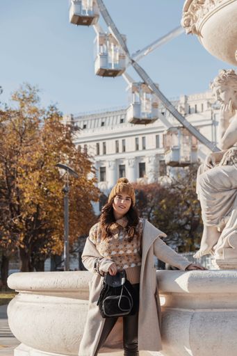 A vertical image of an attractive woman posing in front of Budapest eye ferris wheel during autumn in Budapest, Hungary