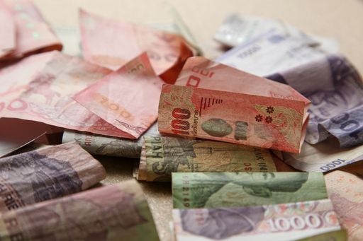 A high angle shot of a pile of banknotes from different countries on a wooden surface