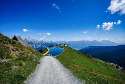 A road leading to a beautiful lake in Leogang surrounded by mountains on a sunny day