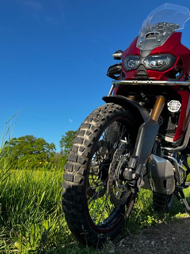 A vertical shot of a CRF1000L Honda Africa Twin adventure bike on a sunny field