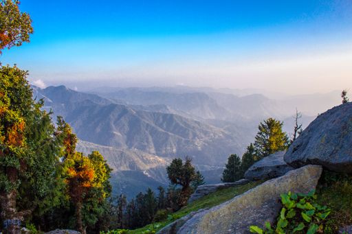 A scenic view of a mountain range covered with greenery at sunrise
