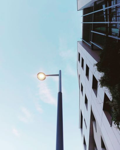 A vertical low angle shot of a street light pole next to buildings against the sky