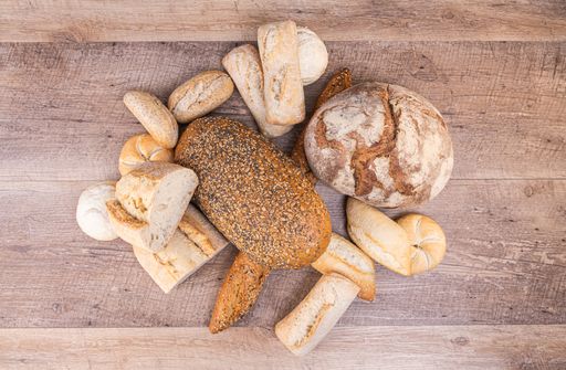 A top view of a variety of bread loaves with sesame and sunflower seeds on a wooden surface