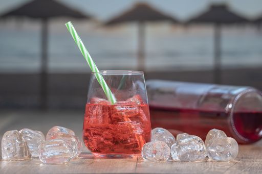 A closeup of a glass of iced cocktail on a wooden table with a blurry background