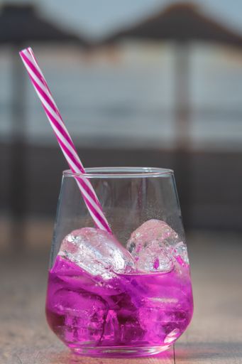 A vertical shot of a glass of iced cocktail on a wooden table with a blurry background