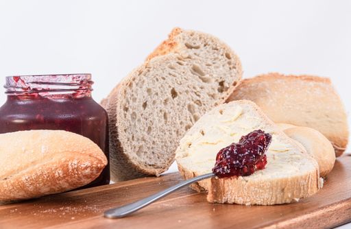 A closeup of bread slices with jam on a wooden board isolated on a white background