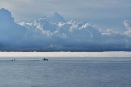 A distant shot of a boat in the sea surrounded by clouds returning to Ramsgate Harbour