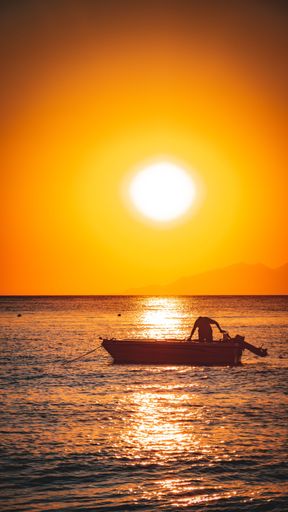 A silhouette of a man in a boat on the sea during the sunset