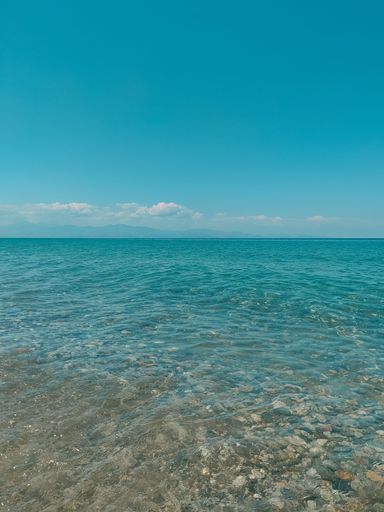 A scenic view of a pebbled beach against the tranquil sea on a sunny day