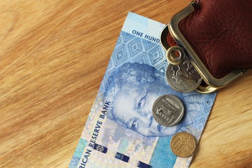 A high angle shot of a leather change purse and some change and a banknote on a wooden surface