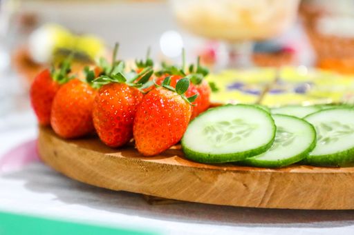 A closeup shot of a Food plate including Strawberry, Salad Cucumber and cheese