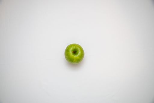 A top view of a single green apple on a white background