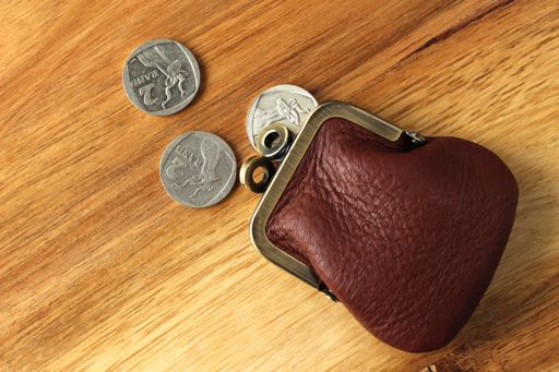A high angle shot of a leather change purse and some coins on a wooden surface