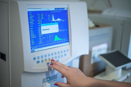 A selective focus shot of a female doctor adjusting the CBC (complete blood count) blood test machine