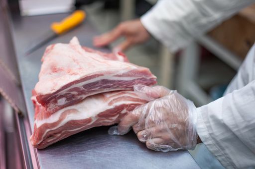 A selective focus shot of the butcher cutting a good piece of pork
