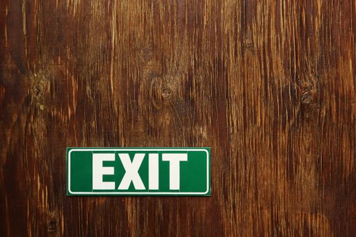 A closeup shot of a green Exit sign on a wooden surface