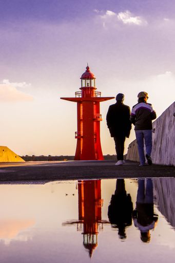 A vertical shot of the people walking to the red lighthouse