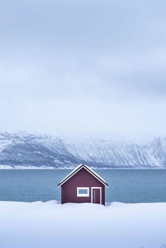 A vertical shot of a tiny house near the lake in winter in Norway