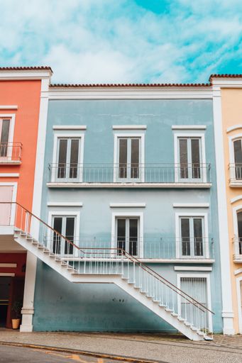 A vertical of a beautiful traditional blue painted old house under the cloudy blue sky
