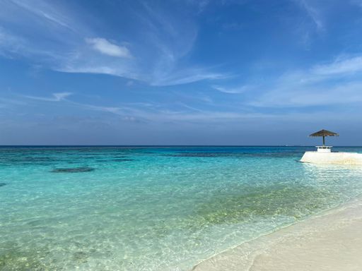 A beautiful view of low, shallow light blue tides at the beach under a sunny sky full of wispy clouds