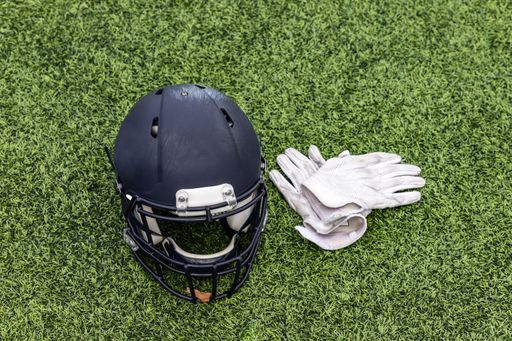 A top view shot of a football helmet and a pair of white gloves on the green grass