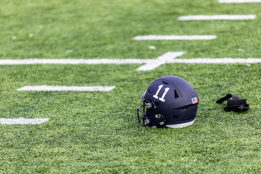 A number 11 American Football helmet and a pair of white gloves laying on the grass