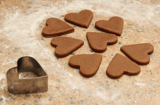 A high angle shot of heart-shaped cookies next to a heart-shaped cookie cutter