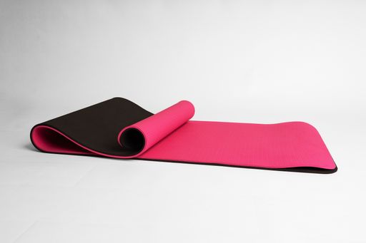 A closeup shot of a pink and black fitness mat isolated on a white background