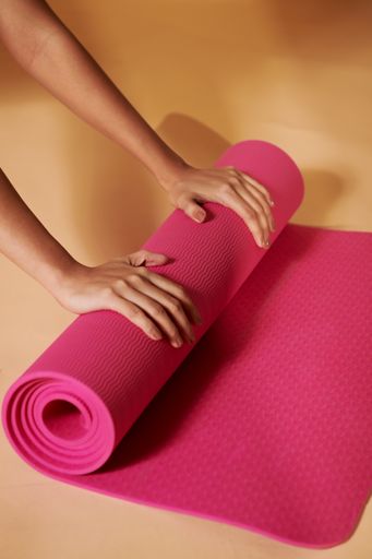 A closeup shot of a female rolling her fitness mat after a yoga