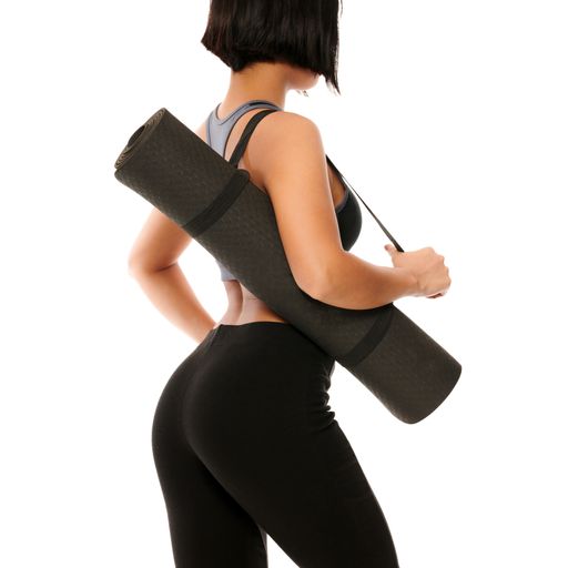A young female in sports wear holding a black yoga mat after exercise