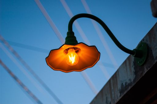 A low angle shot of a vintage glowing lamp on the side of a building