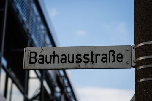 A selective focus of a metallic street sign on the post with " Bauhaus street" written on it