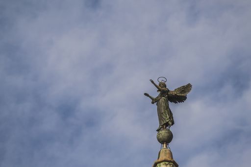 A low angle shot of an angel sculpture on top of Zadar Cathedral Bell Tower