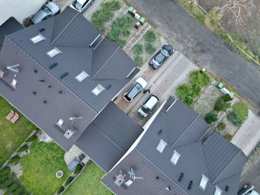 An aerial view of the roofs of buildings with cars parking in front of them