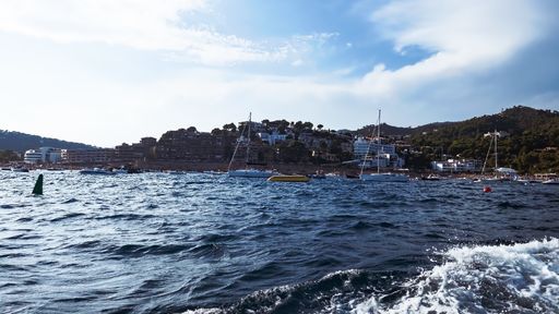A fantastic shot of a wavy sea with many floating boats on mountains background