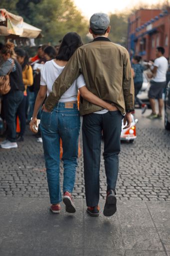 A vertical shot of a beautiful young couple walks hugging on the street