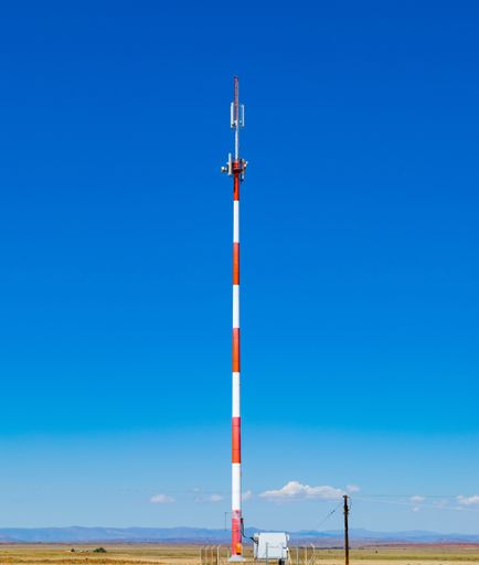 A vertical shot of a telecommunication tower under the clear blue sky