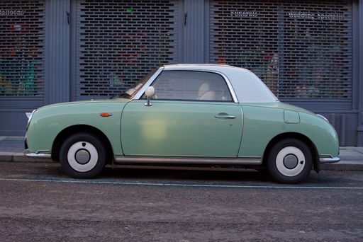 Side view of Nissan Figaro parked on a street in Bray, Ireland. Car produced in Japan in 1991, with emerald green exterior color symbolizing spring.