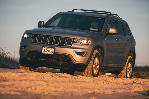 A gray 2018 Jeep Grand Cherokee at the beach at sunset
