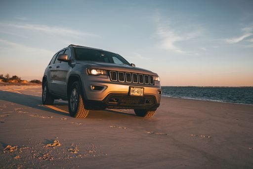 A gray 2018 Jeep Grand Cherokee at the beach at sunset