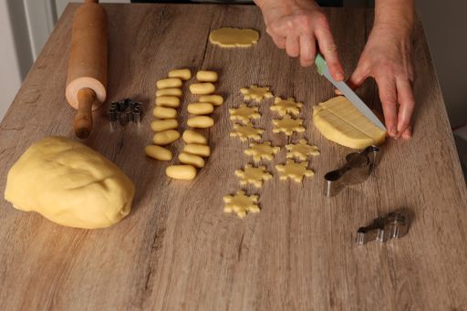 A woman cutting the dough into different Christmas cookie forms