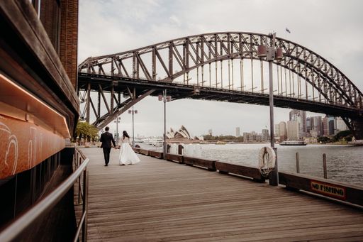 A beautiful shot of a just married couple walking on a wooden path next to a bridge