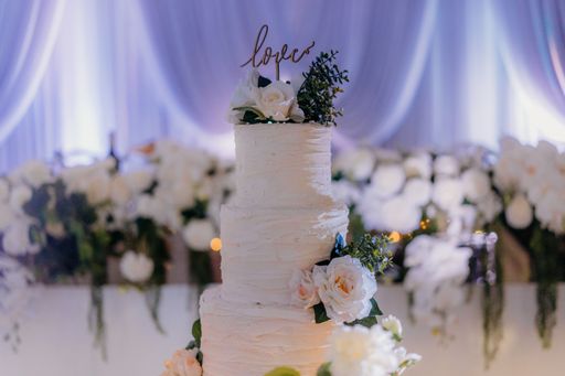 A beautiful three-tier wedding cake with Love topper decorated with flowers