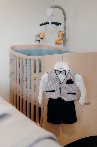 A vertical shot of clothing for a baby boy near the crib
