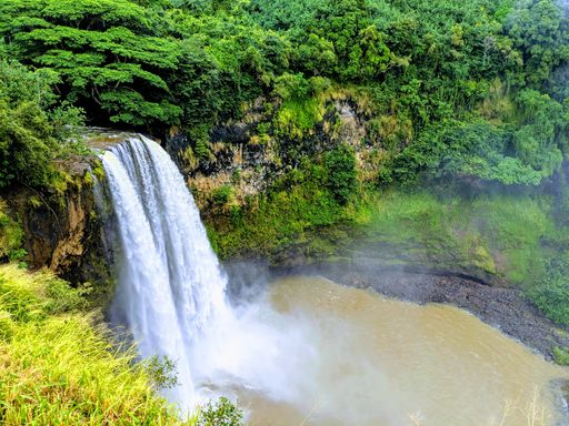 A beautiful view of a foggy waterfall surrounded by vegetation