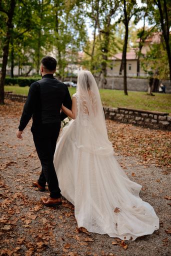 A vertical shot of a groom and a bride walking in the park